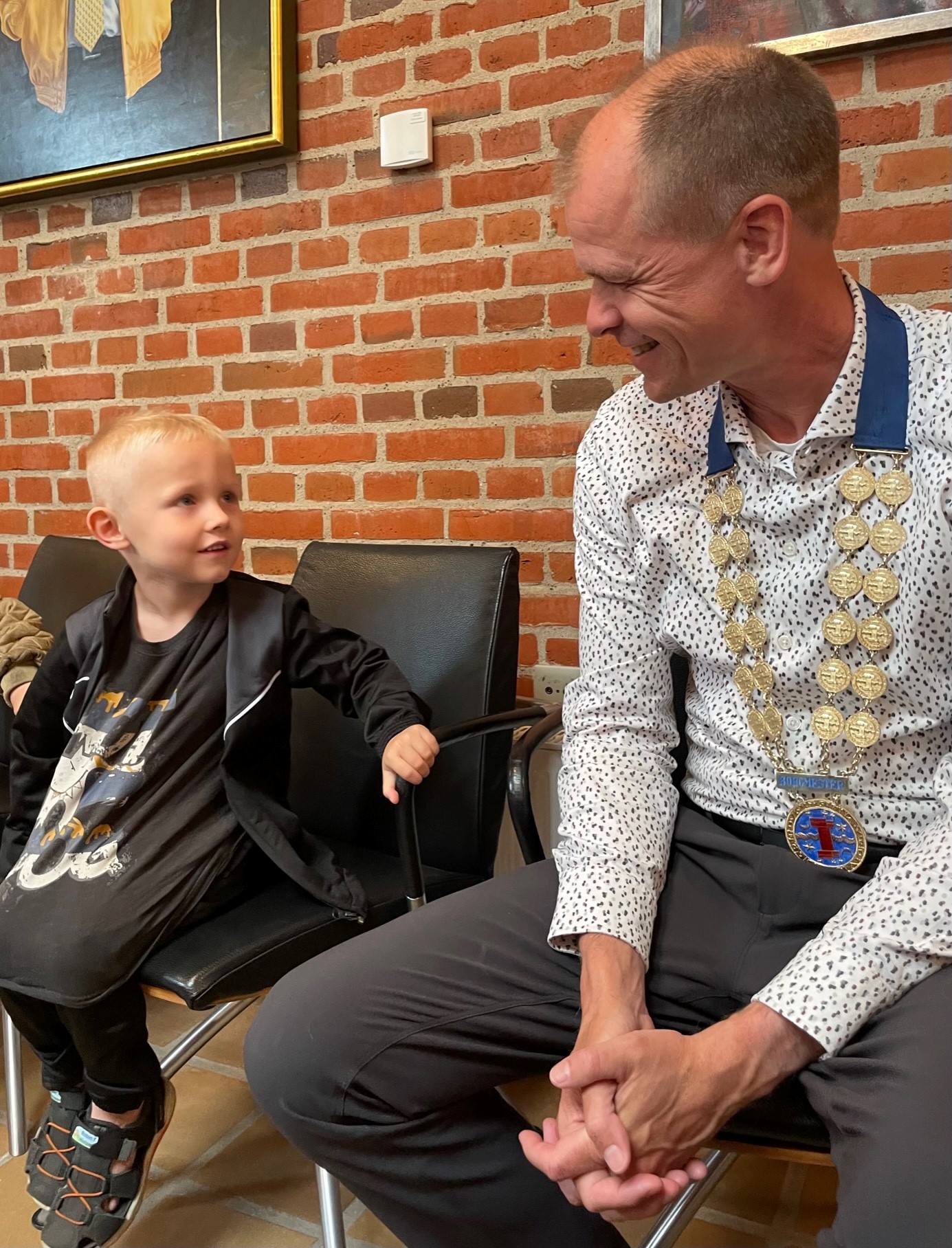 Dreng og borgmesteren sidder ved siden af hinanden
