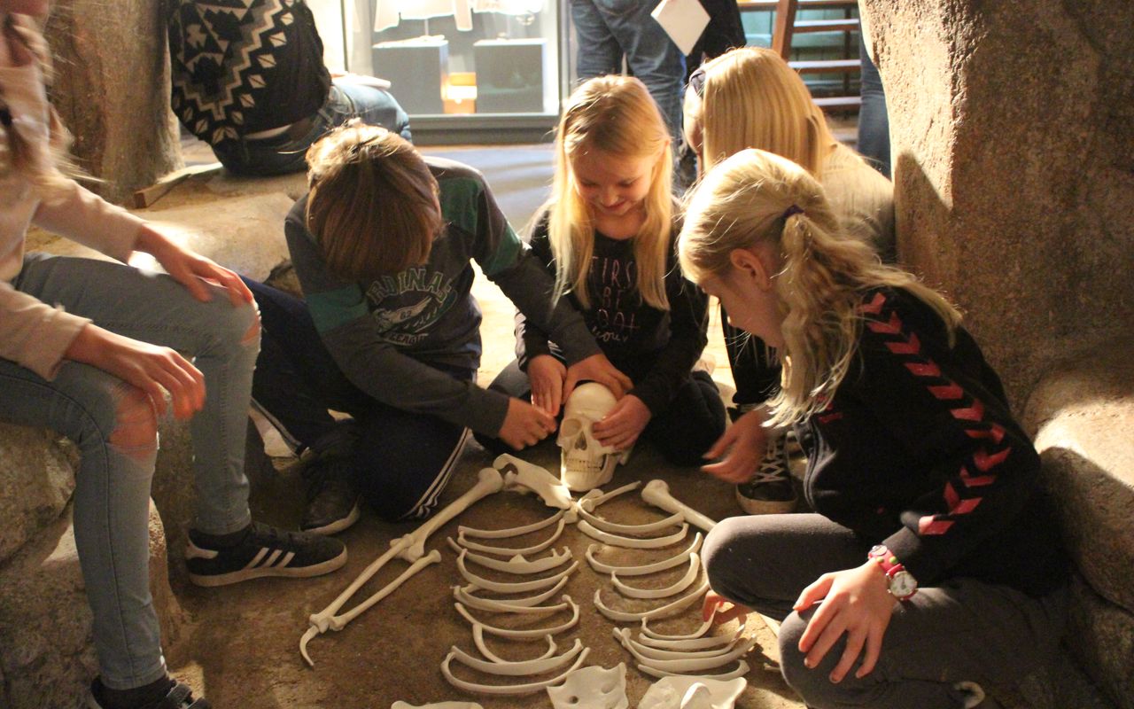 Børn sidder omkring et skelet i museets udstilling i Grenaa